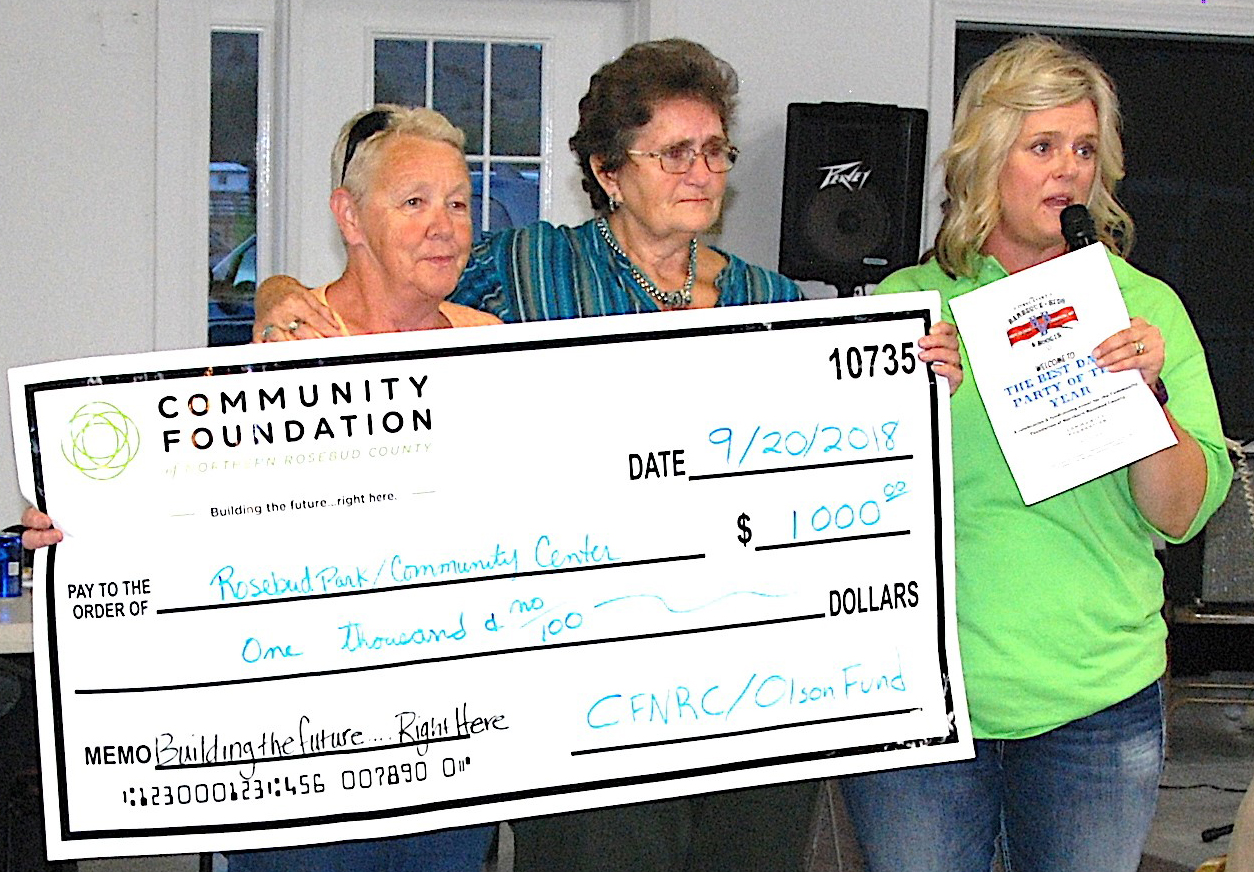 Velma Rice and Jennifer Anderson present an oversized check and award to Lane Buck. 